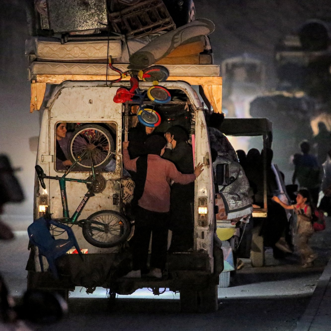 Gens chargent des marchandises dans un véhicule, ambiance nocturne et mouvement.