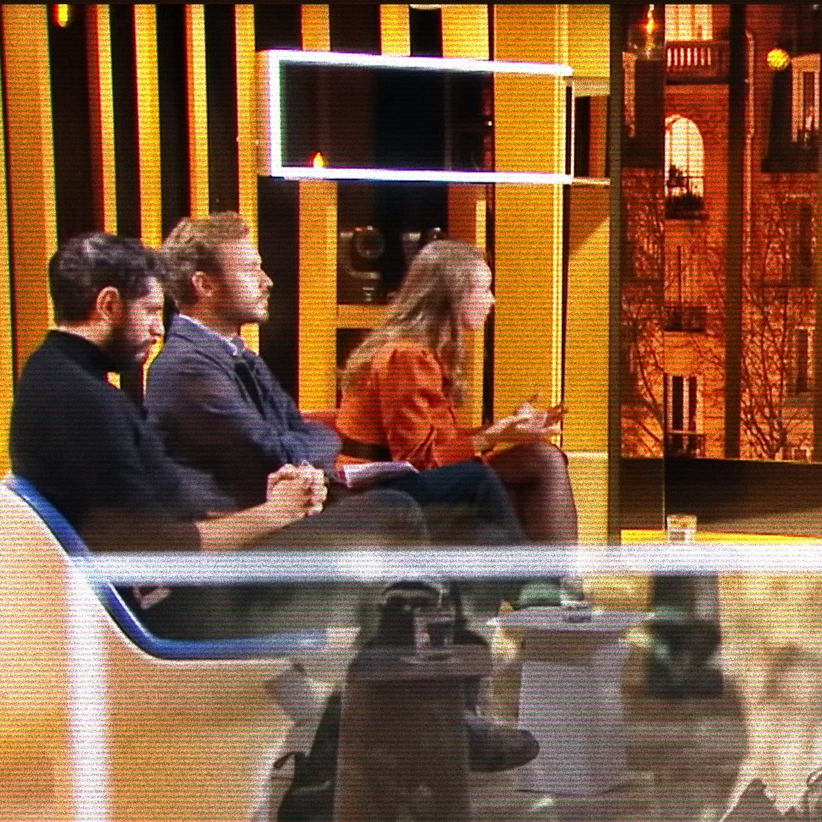 Quatre personnes discutent sur un plateau, avec une vue citadine illuminée en arrière-plan.