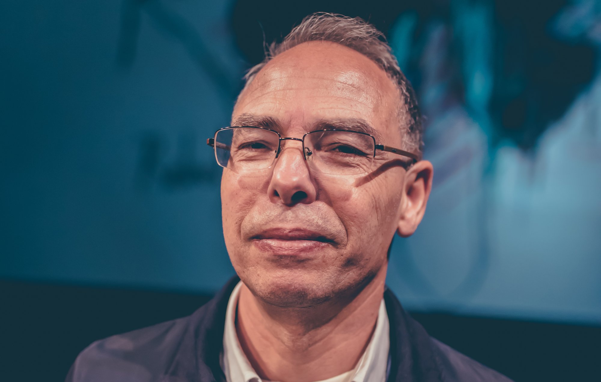 A middle-aged man with glasses and short hair, looking confidently at the camera.