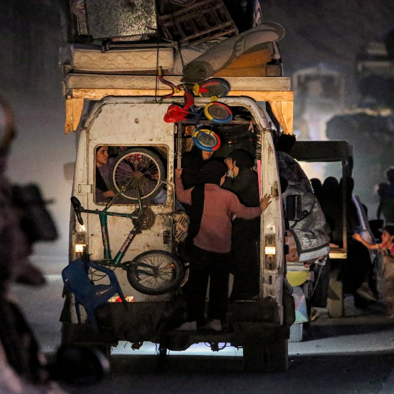 خودرویی در شب با بار زیاد، مردم در حال سوار شدن و پیاده شدن، فضایی شلوغ و پر جنب و جوش.