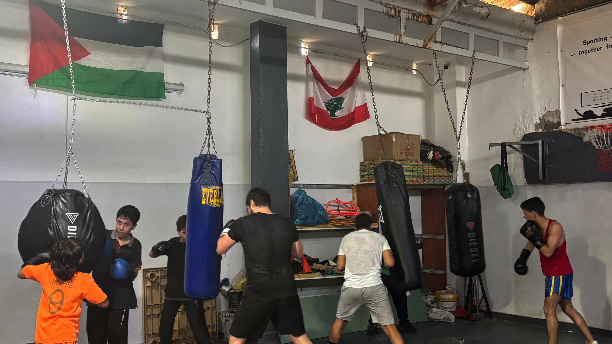 Un groupe de boxeurs s'entraîne dans une salle avec des sacs de frappe.