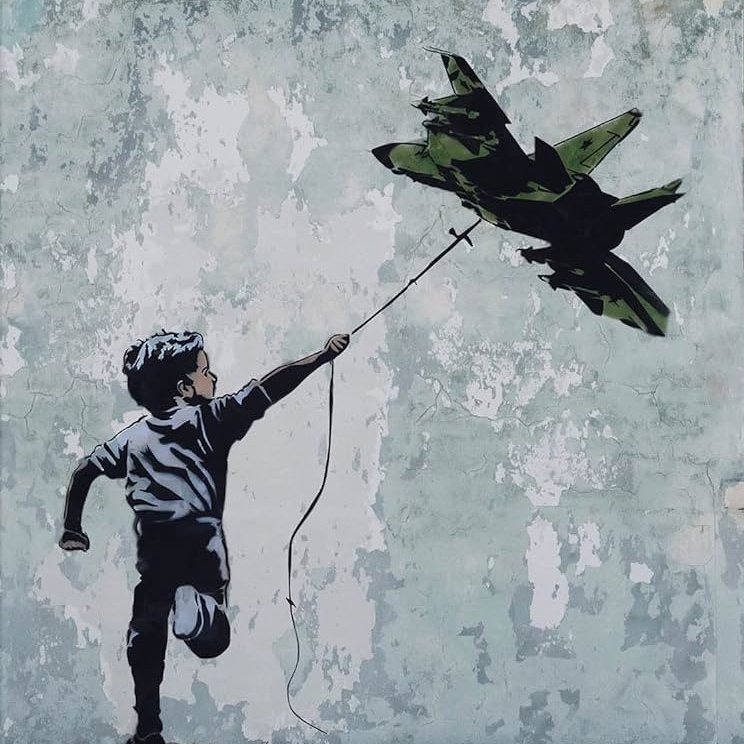 L'immagine rappresenta un bambino che corre e tiene in mano un filo da cui pende un aereo da guerra in miniatura. Il bambino sembra gioioso, mentre lo sfondo è costituito da un muro scrostato con tonalità chiare e imperfezioni visibili. L'aereo, di colore verde militare, contrasta con l'innocenza del bambino e il suo gesto, creando una riflessione evocativa sul tema della guerra e della gioventù.