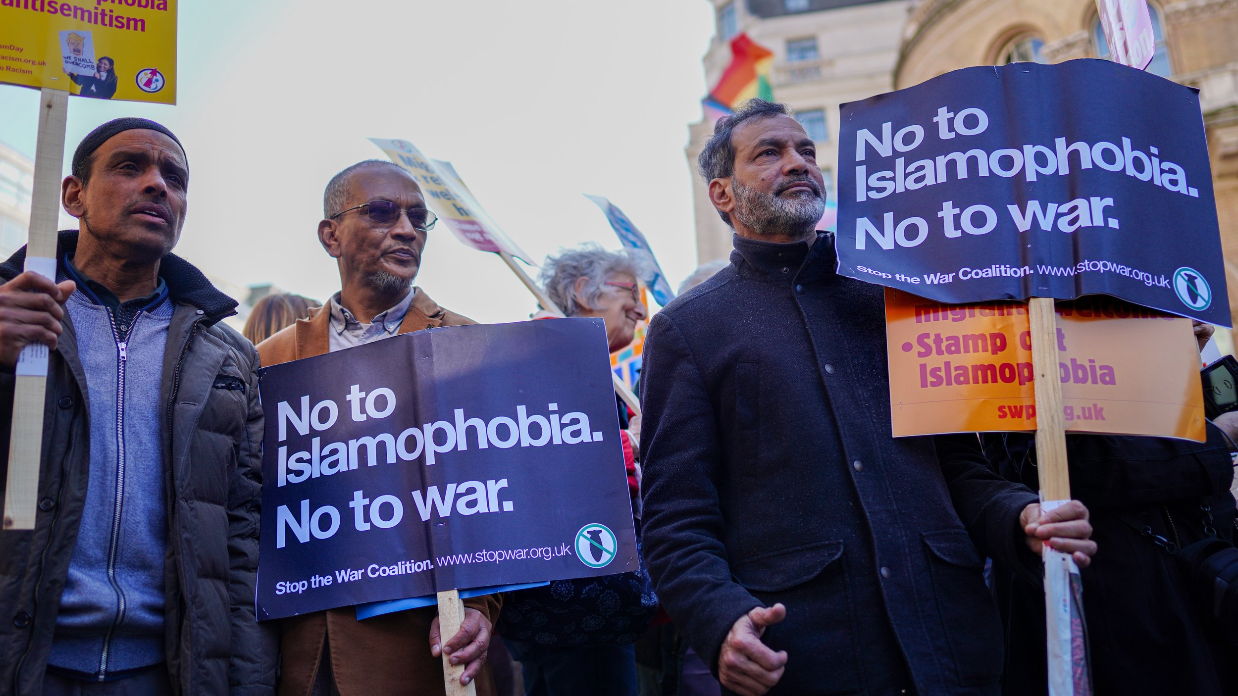 L'image montre un groupe de personnes participant à une manifestation. Elles tiennent des pancartes avec des messages clairs, notamment "No to Islamophobia. No to war." et "Stop the War Coalition". Les manifestants expriment leur opposition à l'islamophobie et à la guerre. On peut voir des personnes de divers âges et origines, toutes unies par leur cause. L'ambiance semble engagée et déterminée.