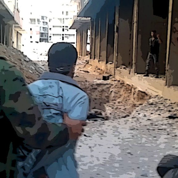 L'image montre une scène de guerre urbaine où deux individus se trouvent dans un environnement dévasté. On peut voir un soldat en uniforme qui tient une personne par l'épaule, tandis qu'un autre homme est visible au loin, apparemment dans une position de menace. Le sol est rempli de décombres, et l'atmosphère générale semble tendue et dangereuse, illustrant les ravages d'un conflit armé. Les bâtiments environnants sont endommagés et abandonnés.