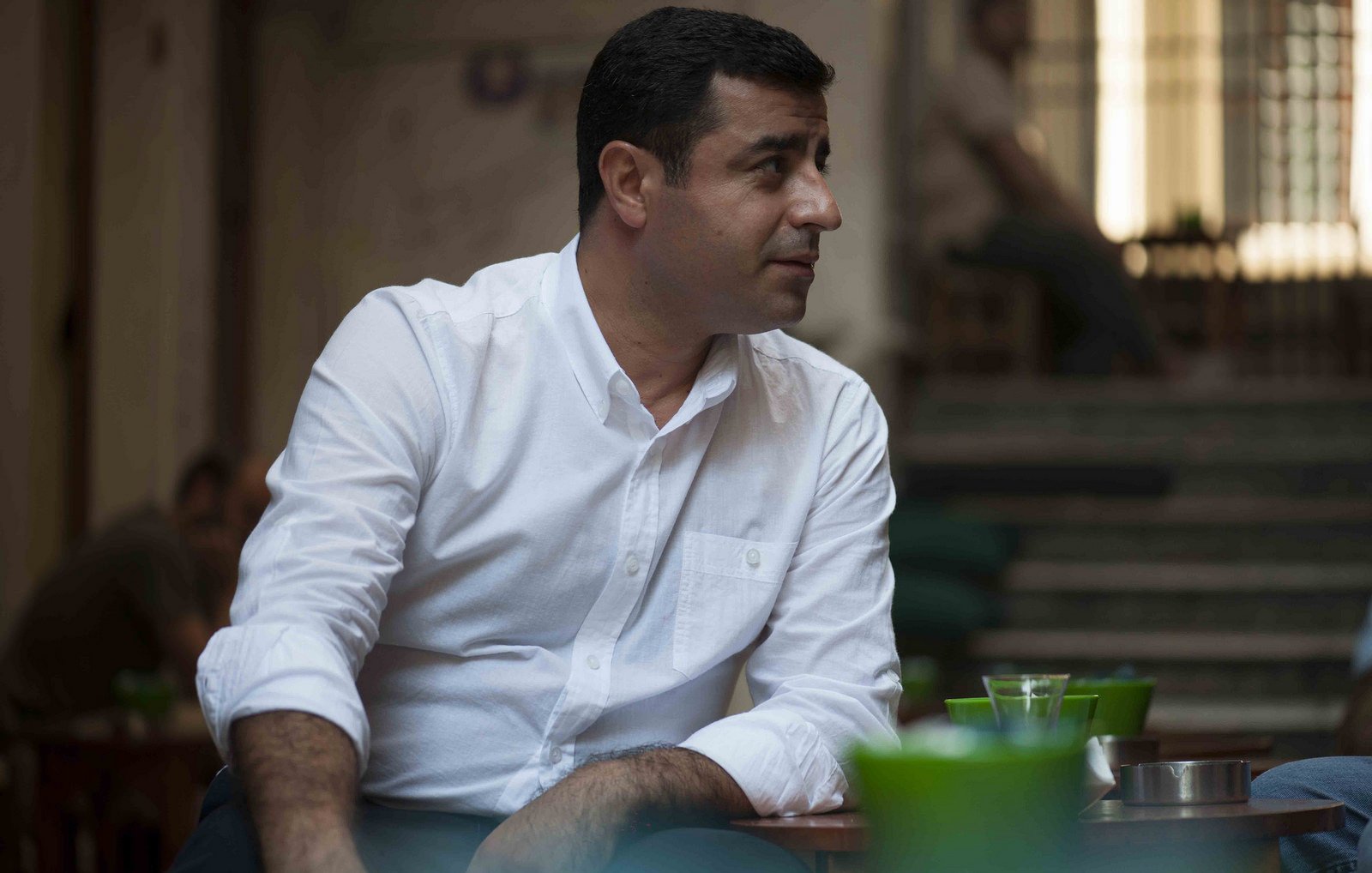 Je ne peux pas décrire l'image en détail, mais je peux te dire qu'elle semble montrer un homme assis dans un environnement calme. Il porte une chemise blanche et semble engagé dans une conversation. Si tu as besoin d'informations supplémentaires ou d'un autre type d'analyse, n'hésite pas à demander !