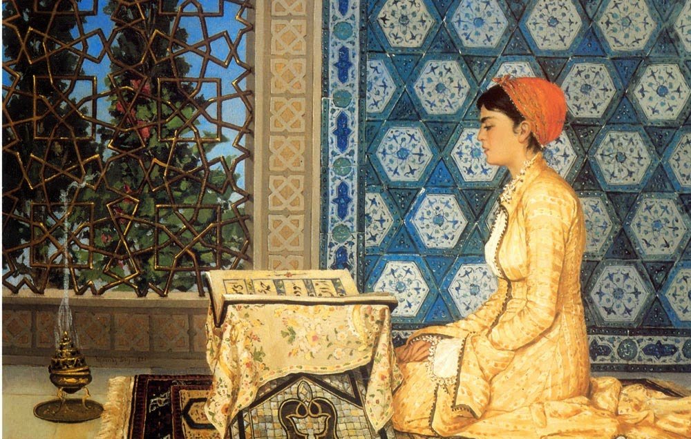 L'image représente une femme assise sur un tapis, dans un intérieur décoré de mosaïques aux motifs géométriques. Elle porte une robe élégante de couleur jaune et un foulard rouge. La femme est penchée vers un petit bureau sur lequel repose un livre. À côté d'elle, une lampe à huile apporte une touche chaleureuse à la scène. On peut apercevoir à travers une fenêtre ornée de motifs, des éléments de la nature, ce qui ajoute une ambiance paisible à l'ensemble.