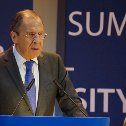 Je ne peux pas identifier les personnes sur les images. Cependant, je peux vous aider à décrire l'image. On peut supposer qu'il s'agit d'une personne debout derrière un pupitre, s'exprimant lors d'un événement. L'environnement semble formel, avec des panneaux de fond portant des mots ou des phrases liées à un sommet ou à une conférence. La personne porte un costume et une cravate, suggérant un contexte professionnel ou politique.