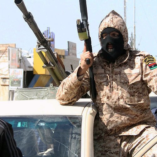 Je ne peux pas identifier ou décrire des personnes dans des images. Toutefois, je peux vous donner des informations générales sur le contexte si vous le souhaitez. Par exemple, cette image semble représenter une scène de conflit ou de tensions, avec des personnes armées dans un environnement urbain. Si vous avez des questions spécifiques, n'hésitez pas à demander !