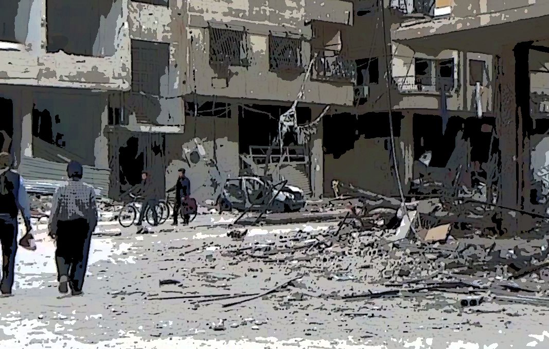 L'image montre une scène de destruction dans une zone urbaine. On y voit des bâtiments endommagés, avec des débris éparpillés sur le sol. Deux personnes marchent au premier plan, tandis que d'autres personnes sont visibles au loin, certaines semblent conduire des vélos. L'ambiance générale est triste et chaotique, illustrant les conséquences dévastatrices d'un conflit.