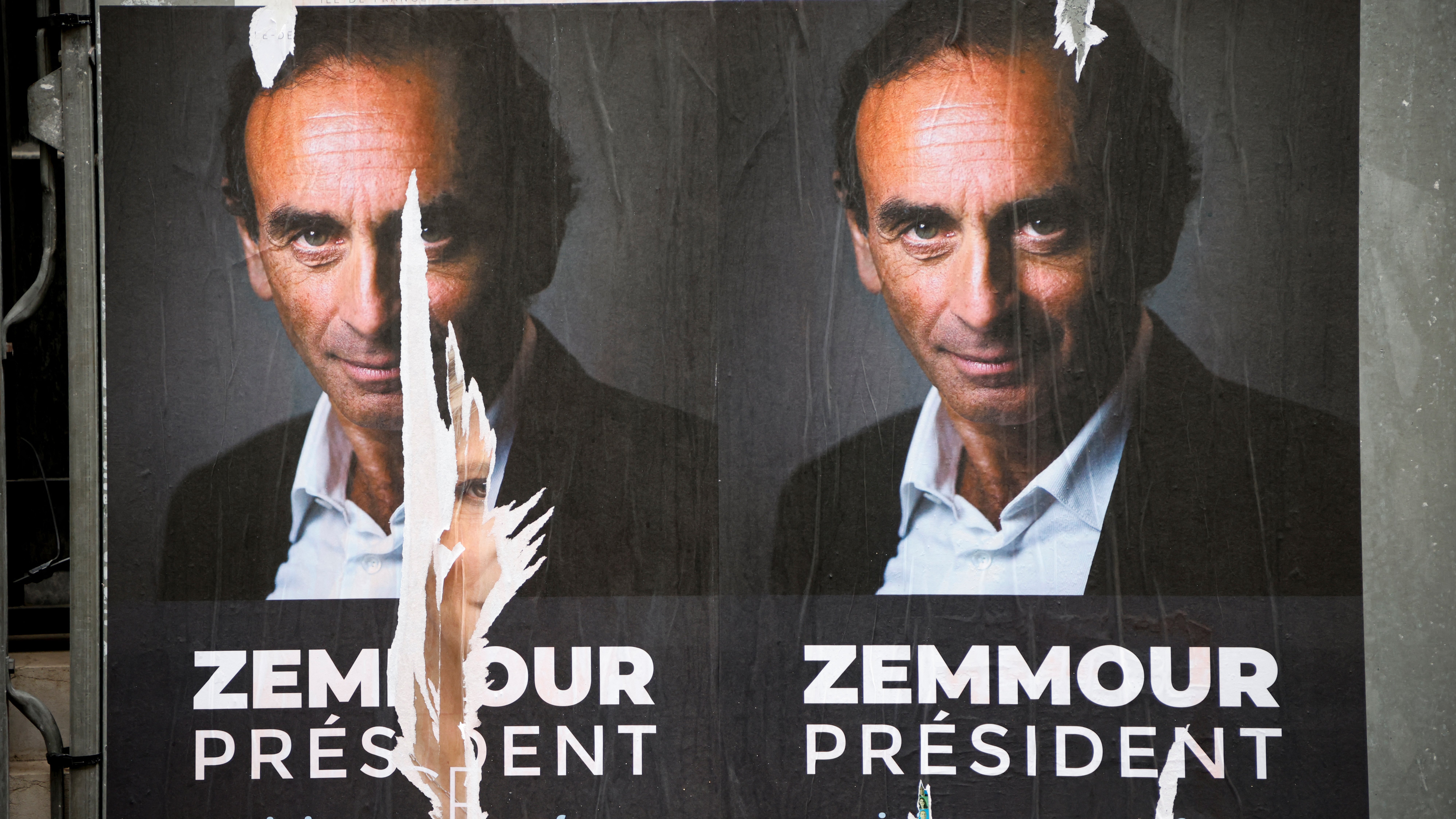 L'image montre une affiche politique présentant un homme qui se présente comme candidat à la présidence. Le visage est affiché en gros plan, et le nom "Zemmour" est écrit en grandes lettres sous le mot "PRÉSIDENT". L'affiche semble avoir été partiellement déchirée, ce qui donne un aspect usé et détérioré. On peut également remarquer un fond sombre qui met en avant le sujet de l'affiche.