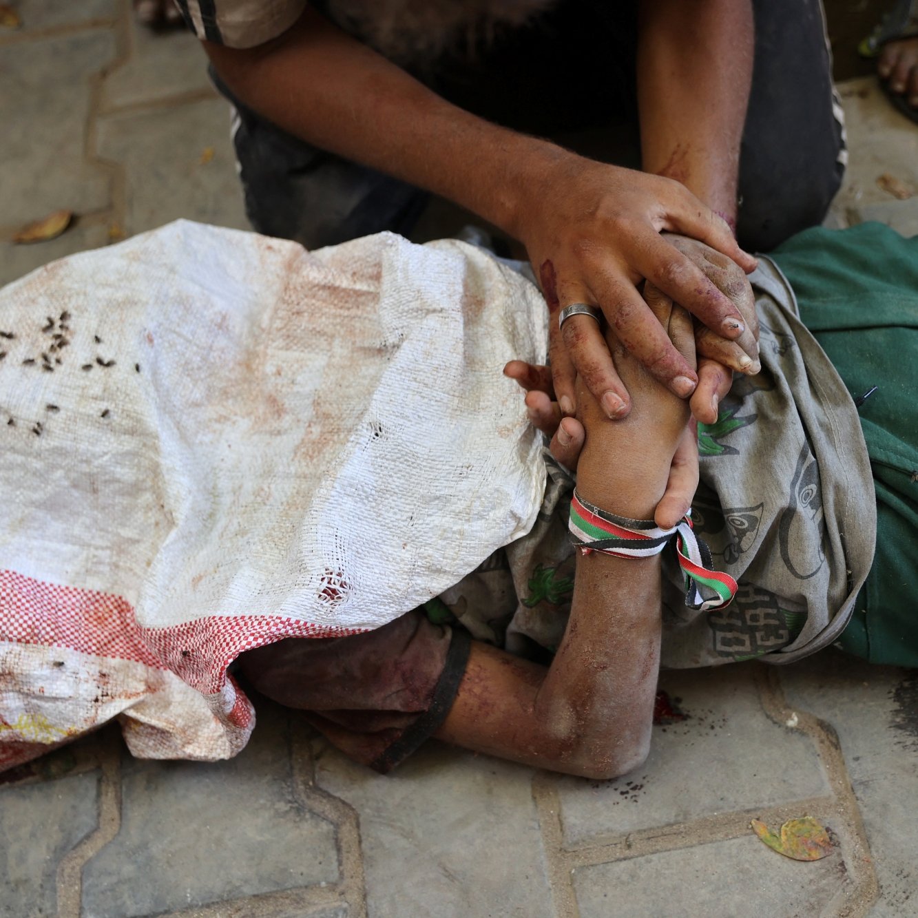 Une personne blessée, allongée au sol, entourée de mains qui l'aident.