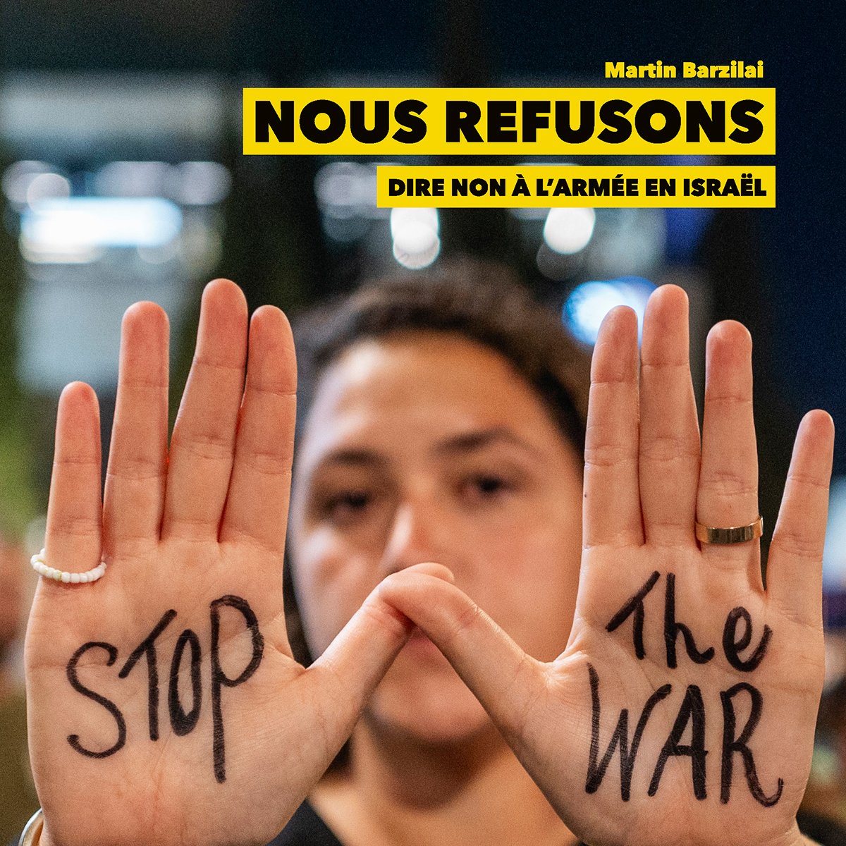 Une personne montre ses mains avec les mots "STOP" et "The WAR" écrits dessus.