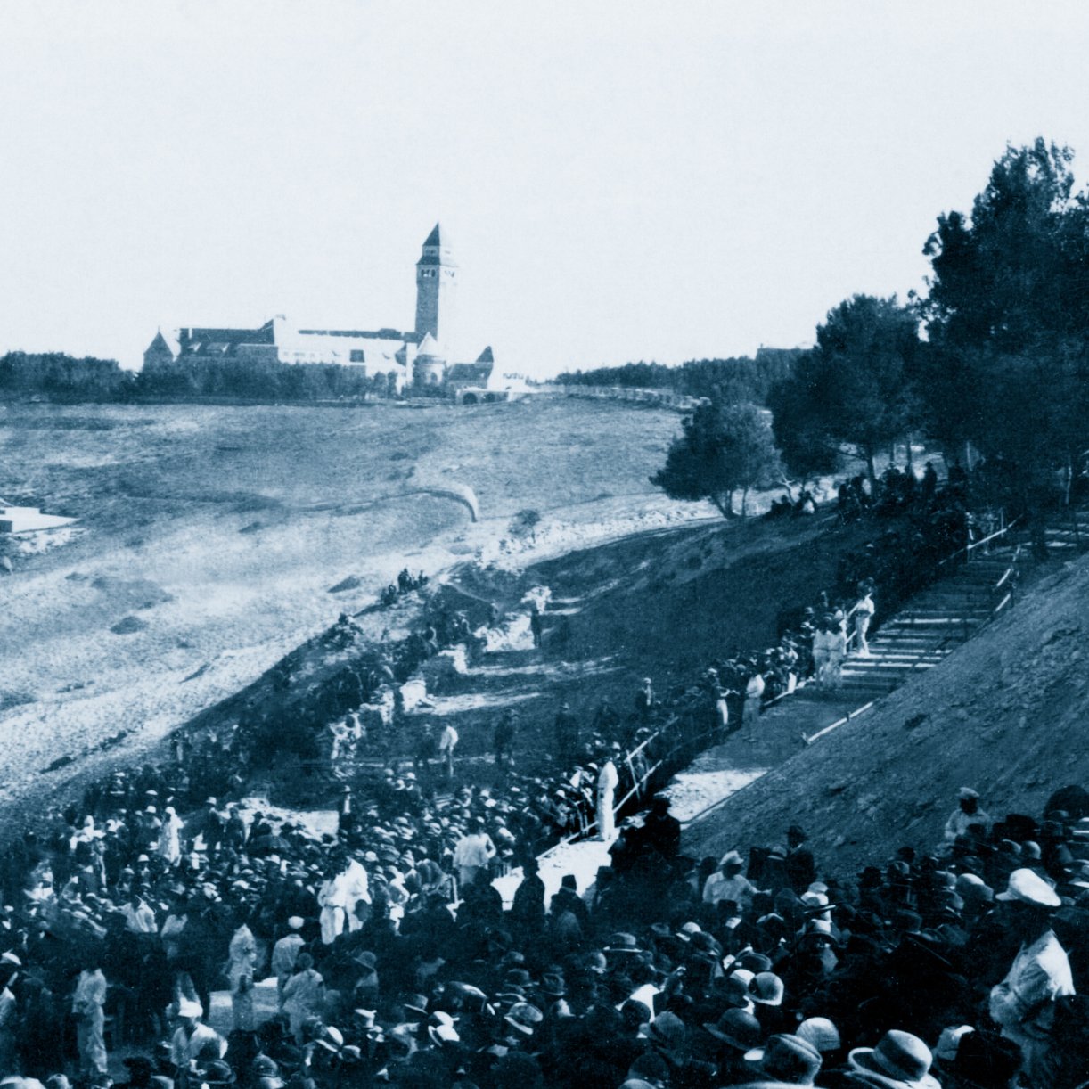 Une foule en bas d'une colline, avec un bâtiment en arrière-plan, scène historique.