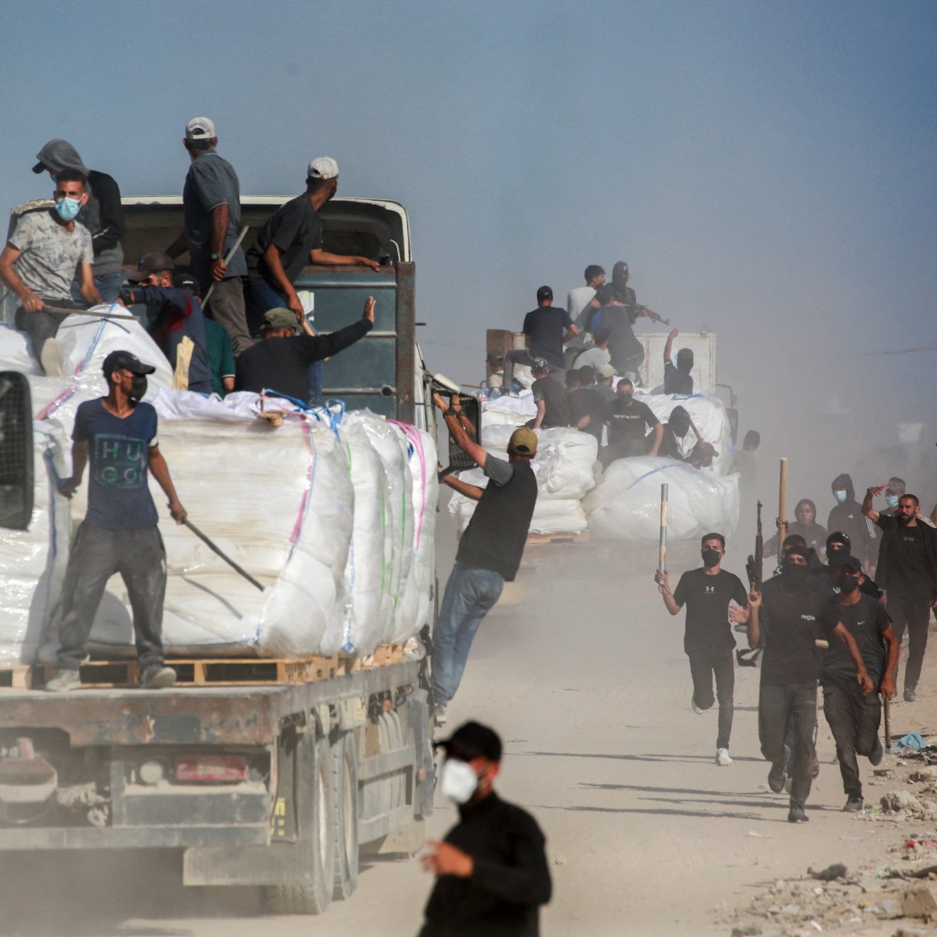 Des camions chargés de marchandises, des travailleurs en mouvement dans la poussière.