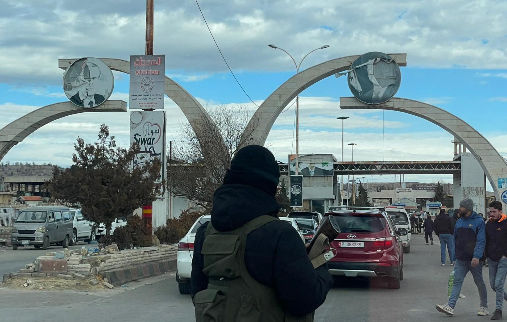 صورة لبوابة كبيرة تتوسطها أعمدة، وأجواء حضرية مزدحمة بالسيارات والمارة.