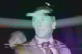 Image floue d'un homme en costume avec des effets de distorsion numérique.