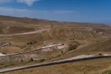 Un chemin sinueux traverse des paysages arides sous un ciel bleu.