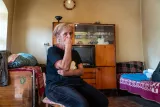 Une femme pensive assise dans une pièce simple avec des meubles rétro.