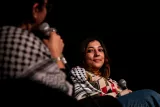 Deux femmes discutent sur scène, l'une sourit en écoutant l'autre.