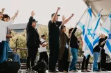 Des personnes se tenant sur scène, levant les bras et brandissant des drapeaux israéliens.