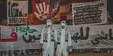 Des manifestants en tenues blanches avec des drapeaux et des pancartes.