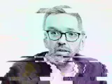 Un homme avec des lunettes, visage flou et pixelisé, semblant surpris ou perplexe.