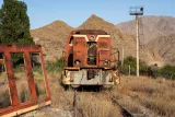 Locomotive rouillée dans un paysage montagneux, entourée de plantes sèches.