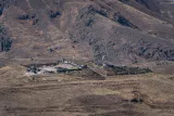 Ruines d'une forteresse sur une colline aride avec des drapeaux.
