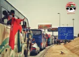 Des bus en cortège, des passagers agitant des drapeaux et souriant.