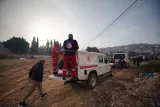 L'image montre des secouristes en uniforme portant des équipements de secours. Ils sont rassemblés autour d'un véhicule de secours, avec un paysage urbain en arrière-plan, sous un ciel légèrement nuageux.