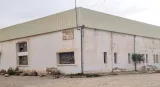 Bâtiment ancien avec murs blancs, toiture verte et quelques moutons autour.