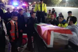 Des personnes entourent des cercueils drapés de drapeaux, un moment solennel.
