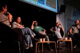 Quatre personnes conversent sur scène, assises, avec un écran en arrière-plan.