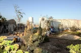 Un camp avec tentes, végétation et réservoir d'eau sous un ciel dégagé.