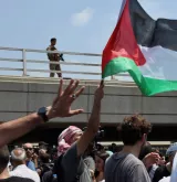Des manifestants avec un drapeau palestinien, un soldat en arrière-plan.
