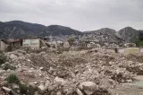 Terrain en friche avec des gravats, montagnes en arrière-plan et villages surplombants.