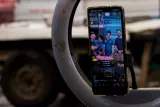 Un téléphone montre quatre personnes souriantes, en arrière-plan un véhicule flou.
