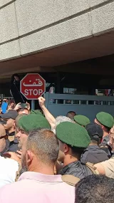 Des manifestants près d'un panneau "STOP", entourés par des forces de sécurité.