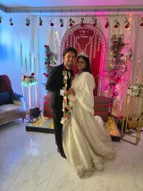 Un couple heureux en costumes de mariage avec décor romantique et éclairage coloré.