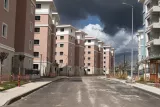 Un chemin désert bordé d'immeubles récents sous un ciel nuageux.