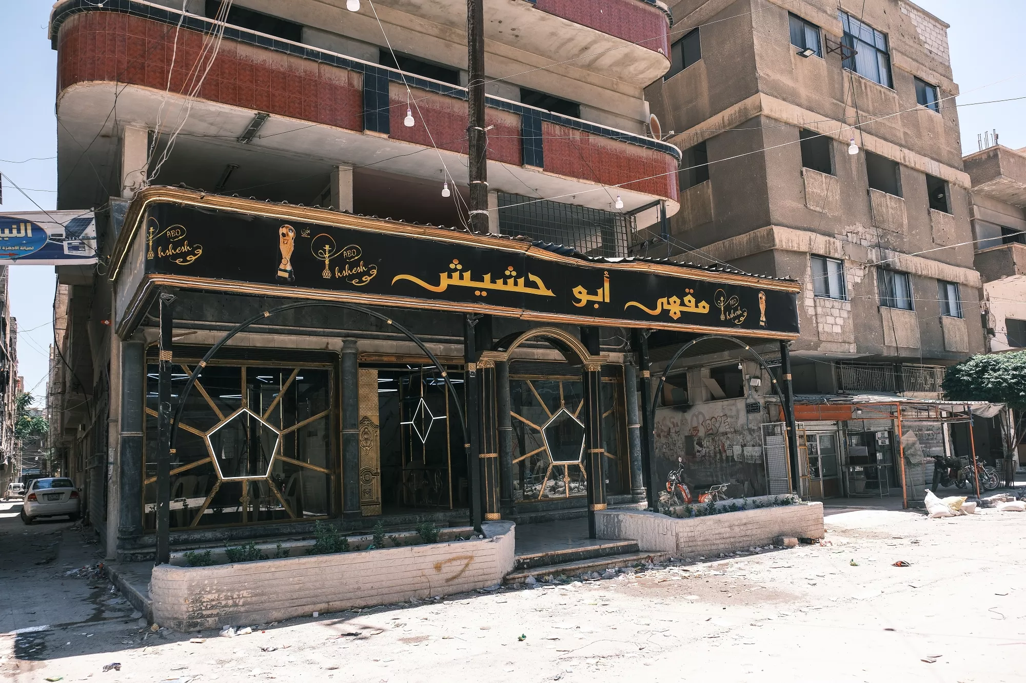 Un caffè dal design moderno con un'insegna nera, situato in una strada deserta.