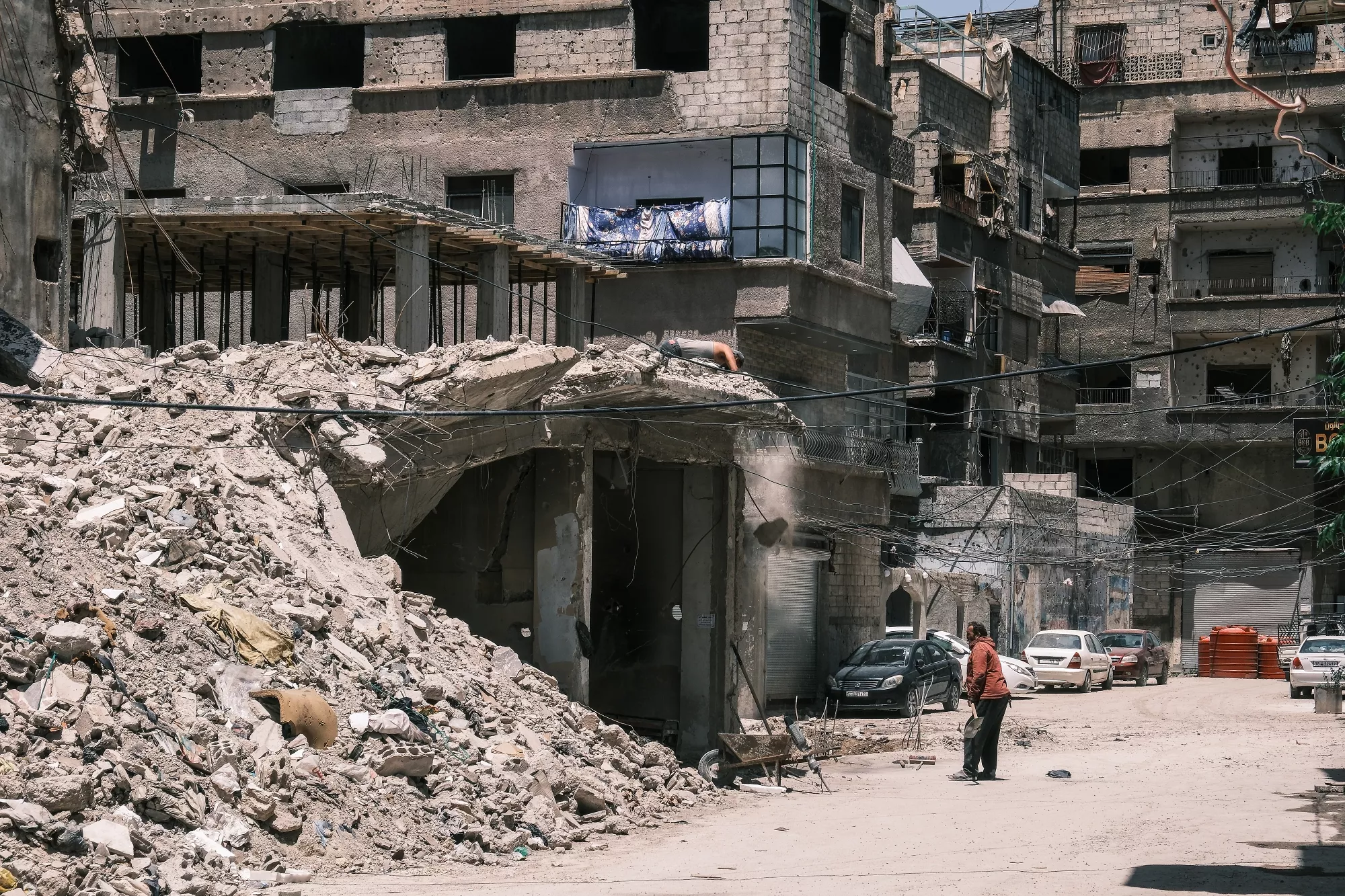 Distruzione di un edificio, detriti sulla strada, un uomo su una strada deserta.