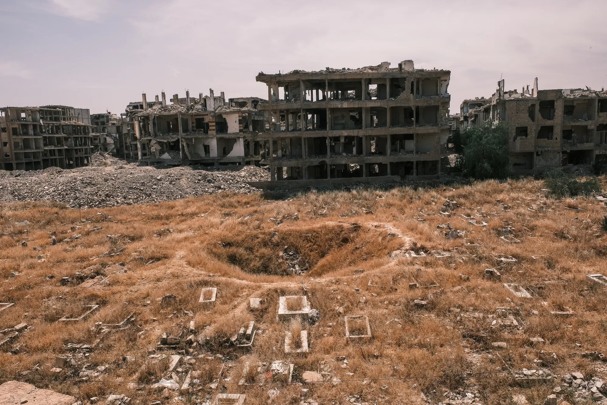 Edifici in rovina circondati da un terreno arido e devastato.