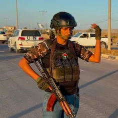 Un uomo in uniforme militare, con un fucile e un elmetto, si erge su una strada.