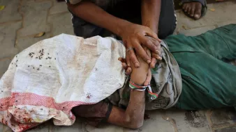 Une personne blessée, allongée au sol, entourée de mains qui l'aident.