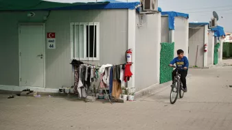 Un enfant à vélo passe près de cabines modulaires et de vêtements accrochés.