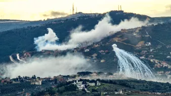 Una collina con case tra nebbia e spruzzi d'acqua, skyline industriale sullo sfondo.