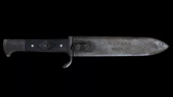 Un couteau avec une lame métallique et un manche noir, gravé d'inscriptions.