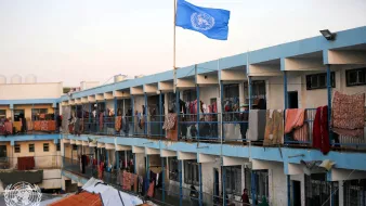 Un edificio con balconi allineati, bandiera ONU e vestiti appesi ad asciugare.