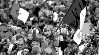 L'immagine ritrae una folla di persone in un contesto di protesta o manifestazione. Al centro, una bambina è sollevata su una spalla e tiene in mano una bandiera, esprimendo un gesto di forza con il pugno chiuso. Gli adulti intorno a lei, alcuni con espressioni determinate, sembrano unirsi a un messaggio comune. La scena è caratterizzata da un forte senso di coinvolgimento e determinazione. L'atmosfera è intensa, con varie bandiere e manifestanti tutti insieme.